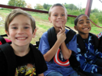 Three happy kids in front of green field